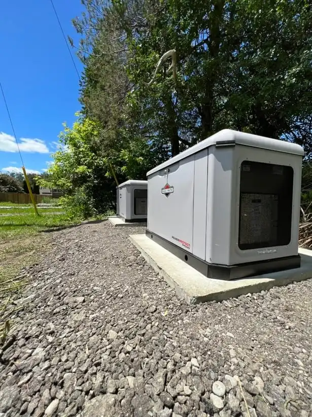 Two standby generators installed on concrete pads at a rural property