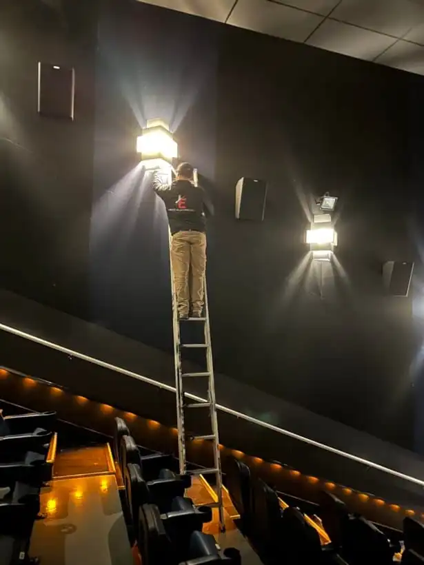 Warm wall sconces glowing in a dark theatre being serviced by an electrician